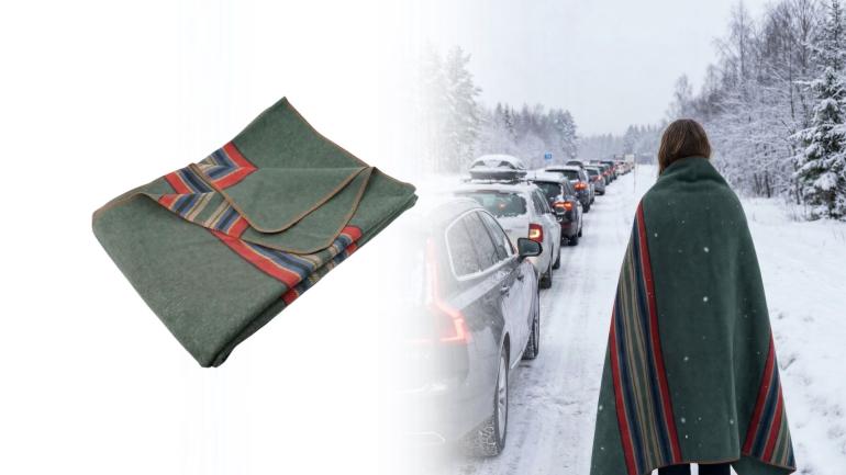 Kvinna med stor ullfilt står utanför sin bil och kollar på bilköerna framför